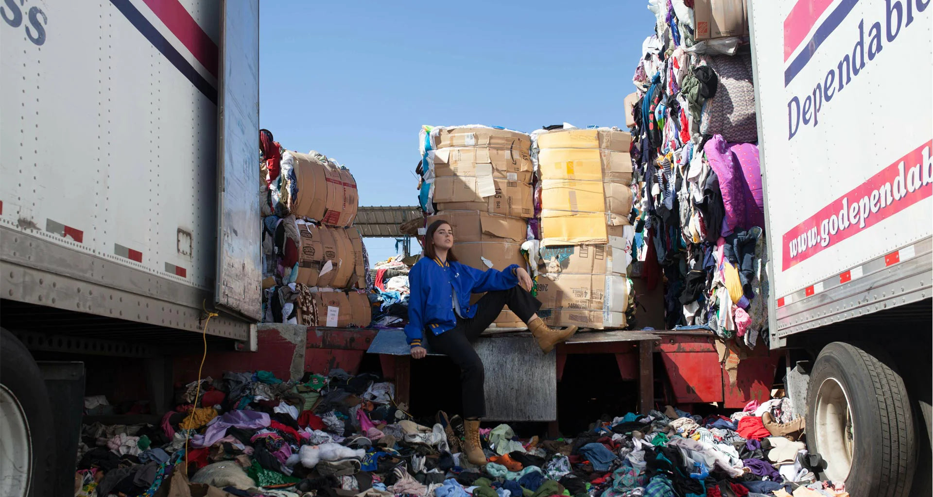 Person sitting on a pile of donated goods next to a truck labeled 'Dependable' with more goods loaded.