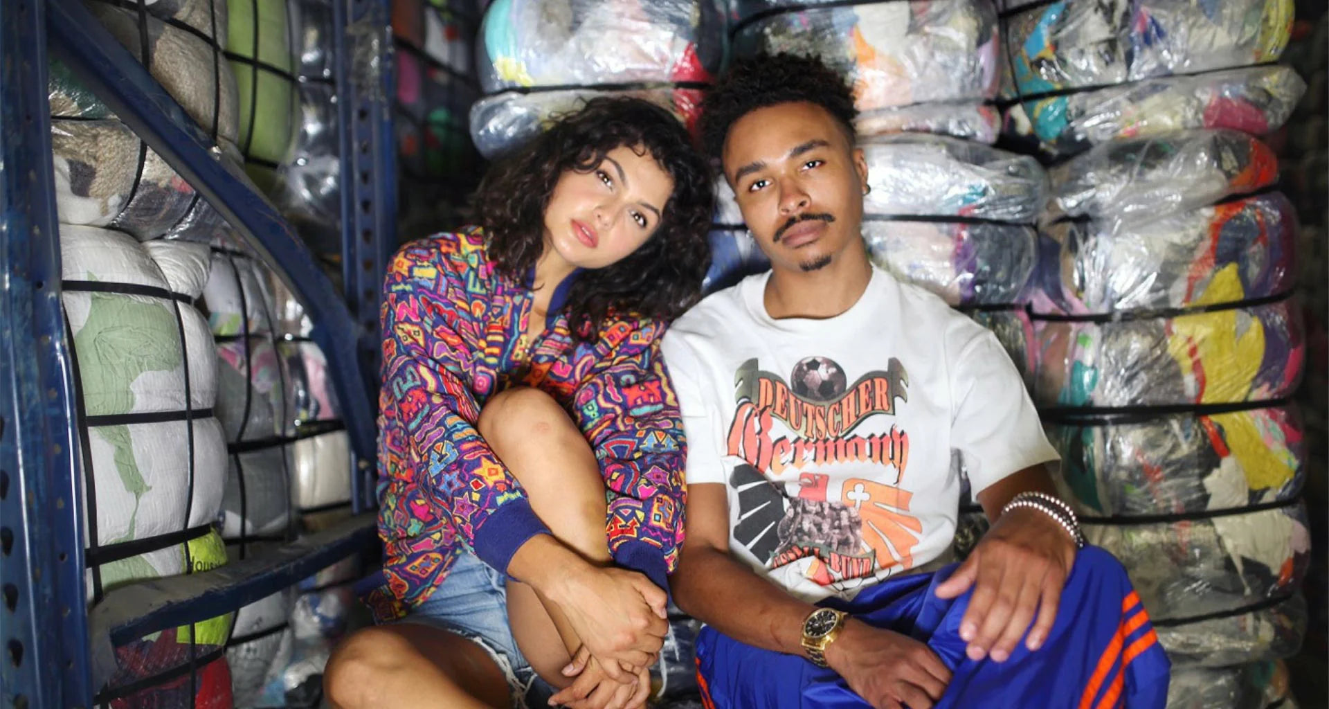 Two people sitting in front of a large number of skateboards.